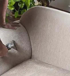 Professional upholstery cleaner deep-cleaning a fabric sofa with a handheld extraction tool and hose Austin, TX.